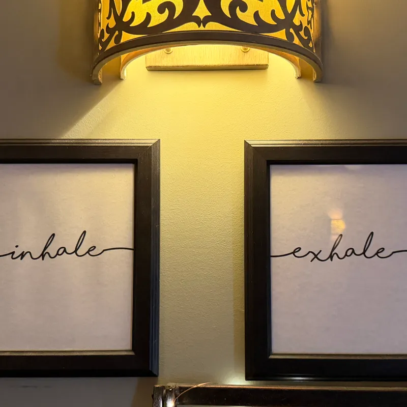 Framed inhale and exhale prints beneath a golden lantern